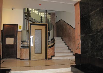 Átrio do edifício, com a escadaria em mármore e o elevador